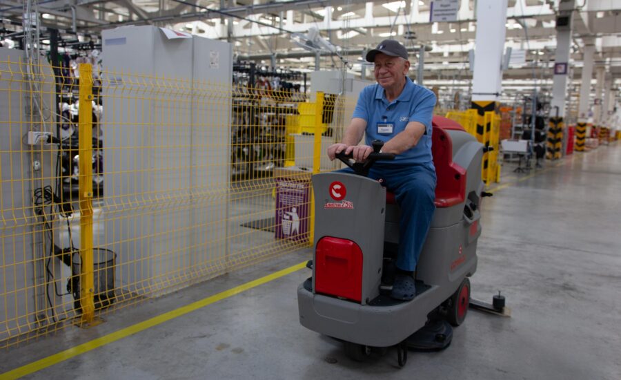 A professional technical cleaning specialist from The Cleaning Pro Group (CPG) in official protective gear cleaning industrial manufacturing equipment from dust and grease.
